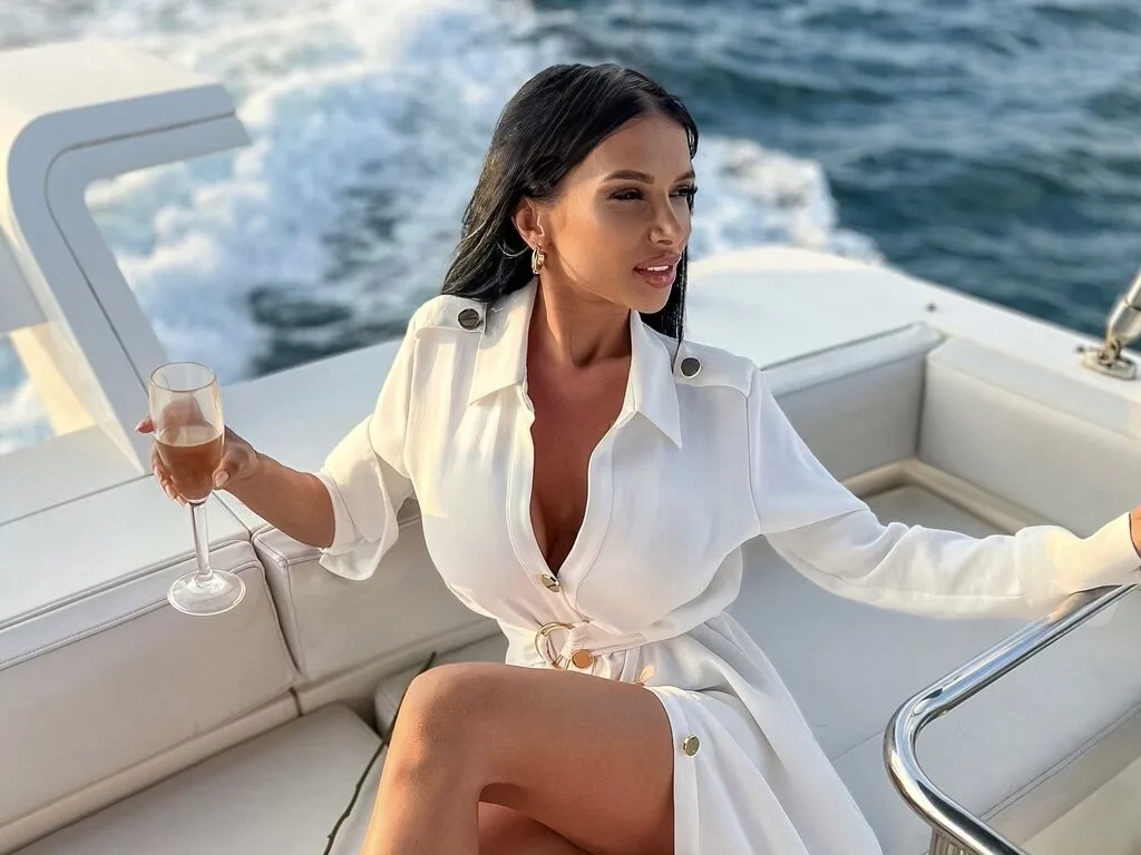 Raisa — Raisa poses in a dark red velvet dress with her hand against her face.