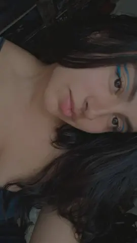 Close-up portrait of a young woman with dark hair and blue eyeliner looking thoughtfully into the camera.