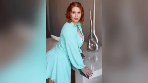 EvieBennet wears a light blue button-down shirt and matching skirt while leaning against a white marble counter.