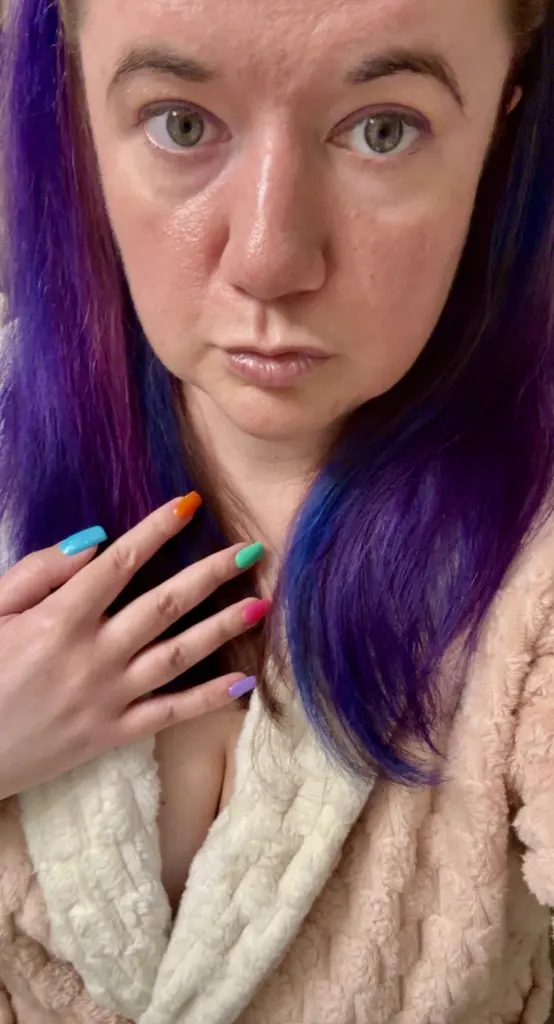 CrystalRivers33 shows her purple-tinted hair and a large, colorful sun tattoo on her shoulder and upper arm.
