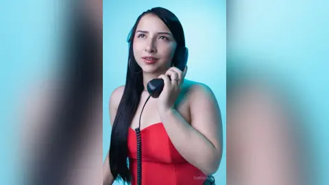 Young woman in a red strapless top holding a vintage telephone against a blue background with a dreamy mood.
