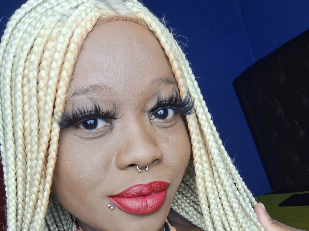 AkeliaHampson with long blonde braids and dramatic eyelashes poses for a close-up selfie.