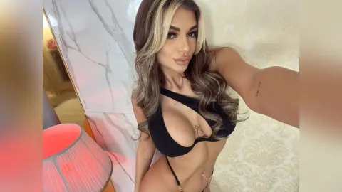 Anastasia poses in a black plunging bikini top and matching bottoms against a patterned wall.