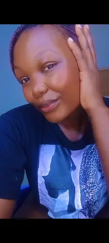 Smiling young woman in a black graphic t-shirt relaxing indoors with a peaceful expression.