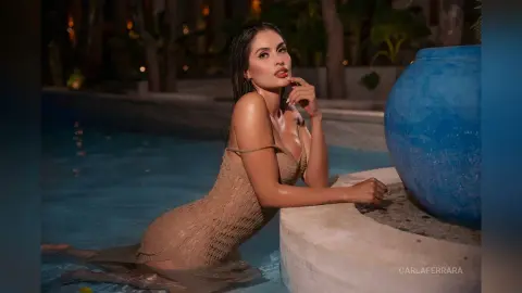 Elegant woman in a tan lace dress relaxing by a luxury poolside at night.