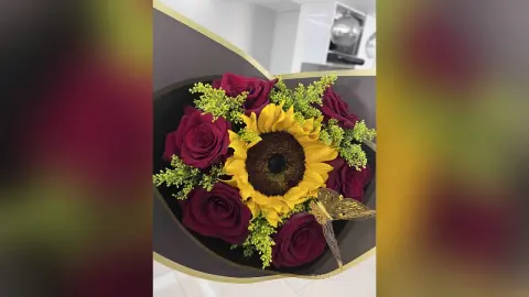 Beautiful floral bouquet featuring bright yellow sunflowers and deep red roses in a romantic arrangement.
