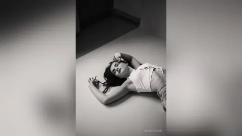 SamaraAdam lies on the floor in a white crop top, looking up with her arms stretched out around her head.