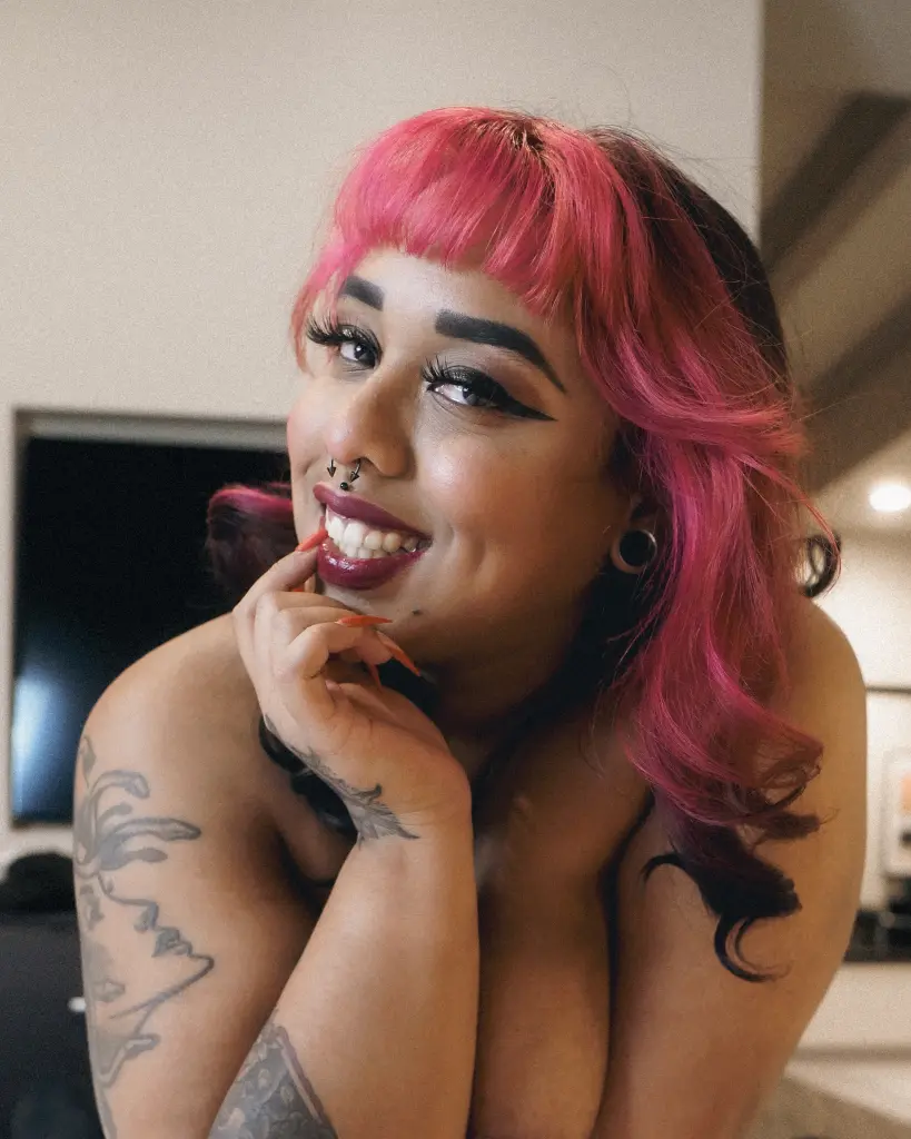 NaomiViolet69 poses with long red hair, wearing a white lace bra that shows her cleavage and bare shoulders.