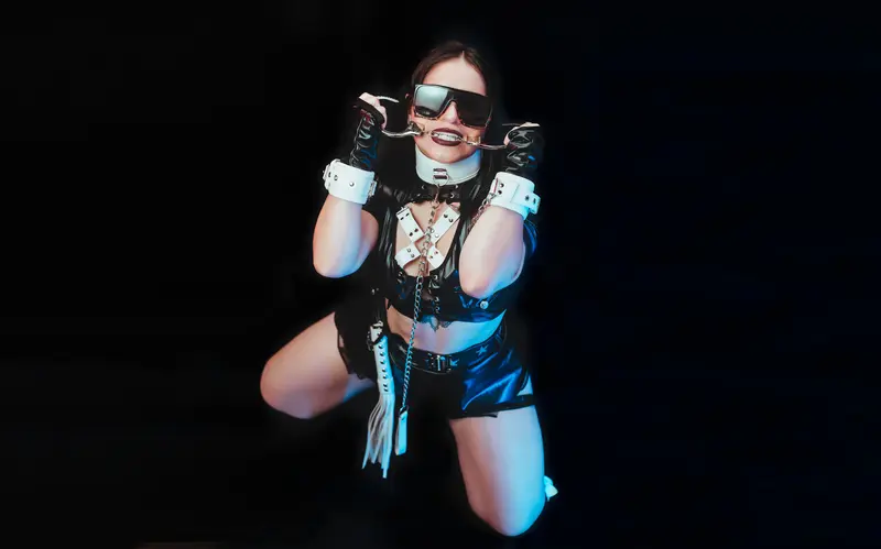 AbbyShinee poses in black lingerie with white trim, showing her breasts and pussy while looking at the camera against a black background.