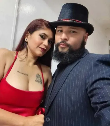 Stylish couple in elegant evening attire posing for a romantic selfie indoors.