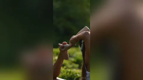 A person receiving a relaxing foot massage in a lush, green outdoor garden setting.
