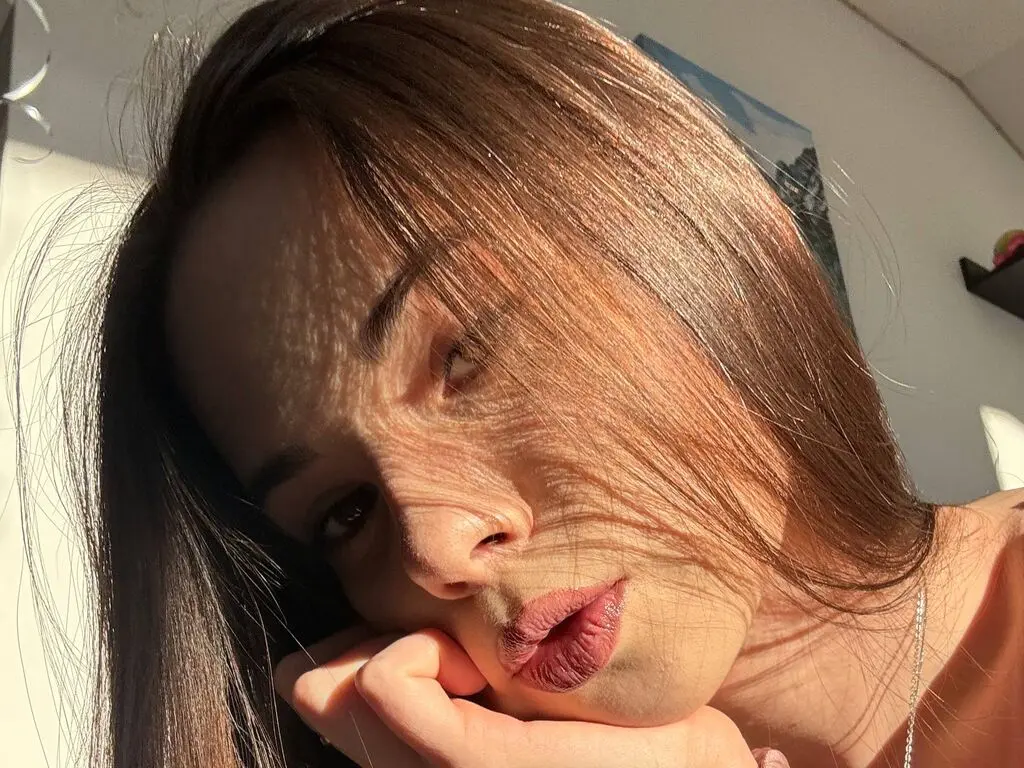 Close-up portrait of a young woman with long brown hair basking in warm, cinematic sunlight.