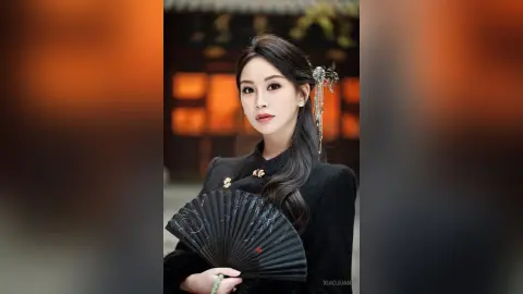 Elegant woman in traditional black Hanfu holding a folding fan in a classic oriental setting.