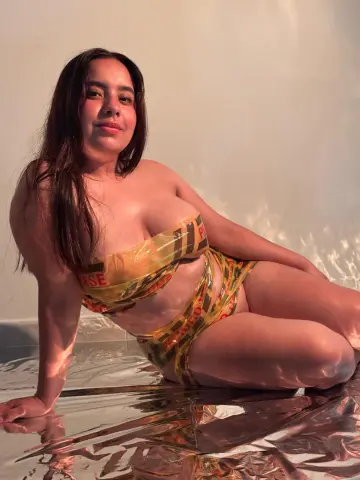 Young woman in a yellow patterned bikini lounging on a reflective silver floor in warm sunlight.