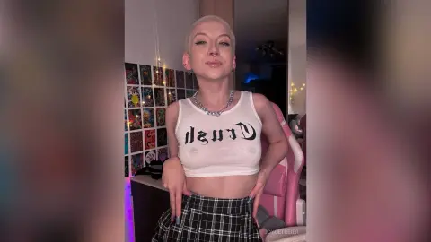 JoyceTreier is a blonde woman in a white crop top and plaid skirt posing in her room.