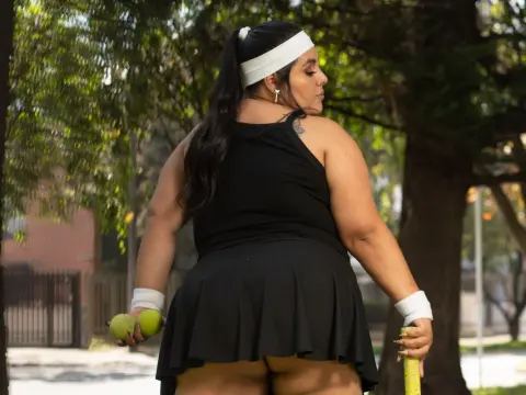 Curvy woman in black athletic outfit holding avocados in a sunny outdoor park setting.
