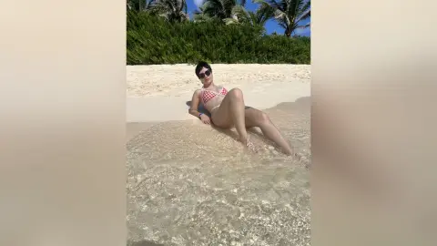 Young woman in a red bikini relaxing on a sunny tropical beach with clear turquoise water.