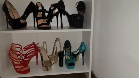 DouceLeya displays a collection of high-heeled shoes, including black, red, gold, and blue platform sandals and pumps arranged on white shelves.