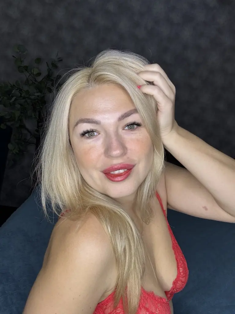 HelenLovememore with blonde hair biting into a juicy red strawberry.