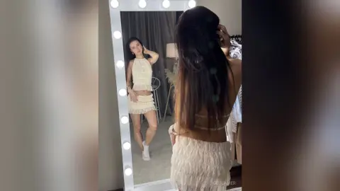 Young woman in a cream lace co-ord set posing in a mirror for a stylish lifestyle aesthetic.