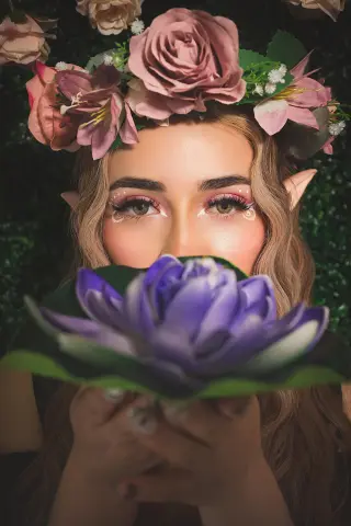 Ethereal elf woman with floral crown and purple flower holding a dreamy, mystical garden pose.