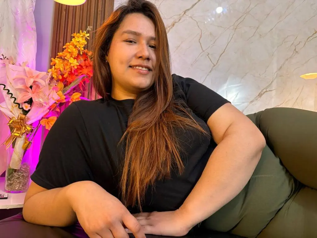 Smiling woman in a black t-shirt relaxing on a green sofa in a bright, modern living room.