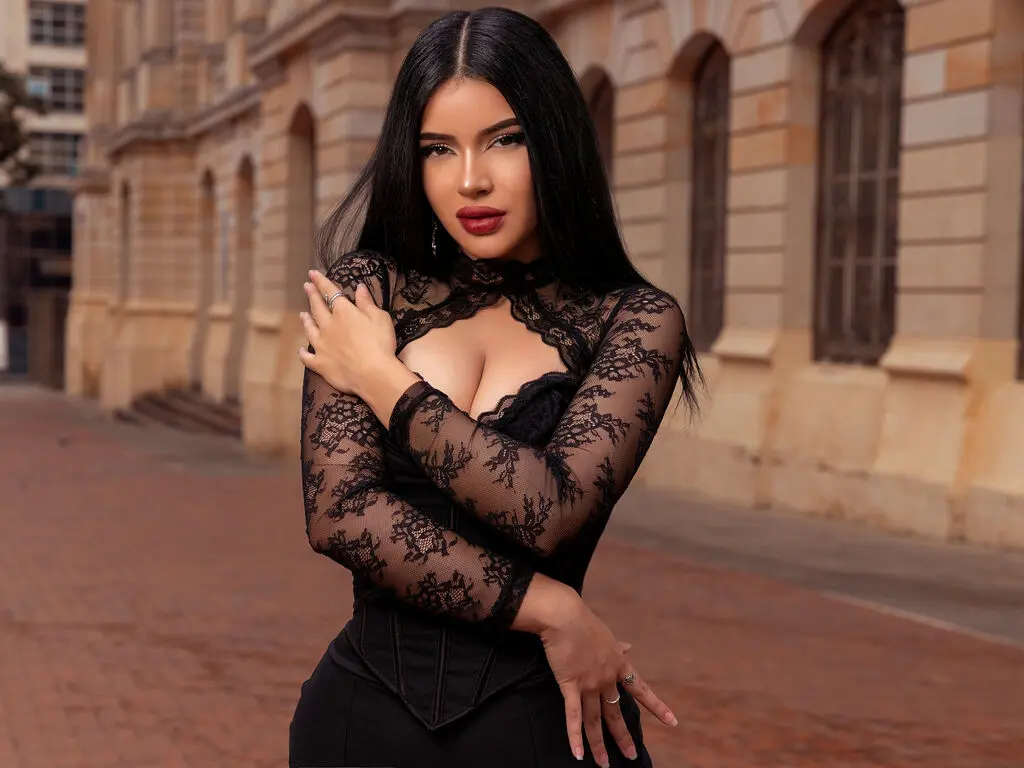 Elegant woman in a black lace long-sleeve top posing confidently against a classic European building background.