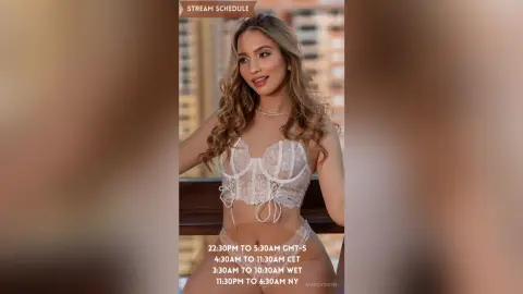 Beautiful woman in white lace lingerie posing on a balcony with a city skyline view.