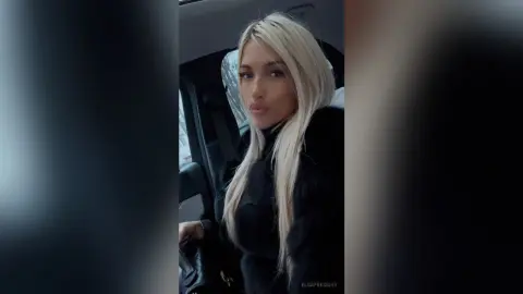 Blonde woman in a black turtleneck sitting in a car with a moody, cinematic aesthetic.