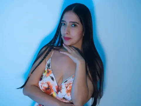 Young woman in a floral print sundress posing against a blue background with soft studio lighting.