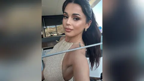 Glamorous woman in a shimmering gold halter top posing on a sunny boat trip.