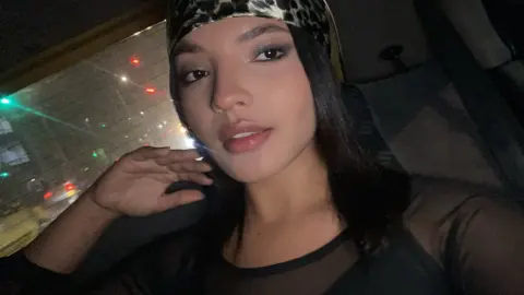 Katalinax_Rose wearing a leopard print headband and a black top while sitting in a car at night.