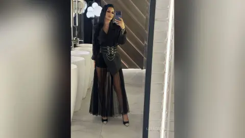 LeyaGrifin takes a mirror selfie wearing a black blazer, a wide belt, and a long sheer skirt.