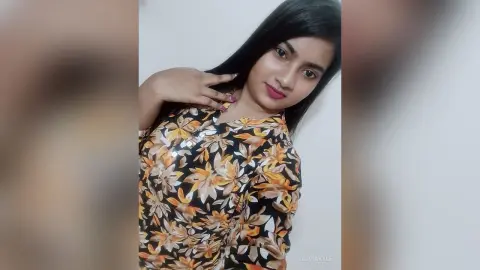 Young woman in a floral print blouse smiling against a plain white background.
