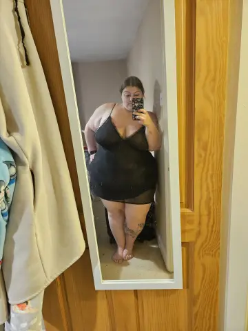 CurvesWithBBW takes a mirror selfie wearing a short black lace slip dress that shows off her curves and legs.