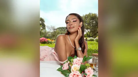 Elegant woman in a pink dress relaxing at an outdoor garden brunch with roses and drinks.