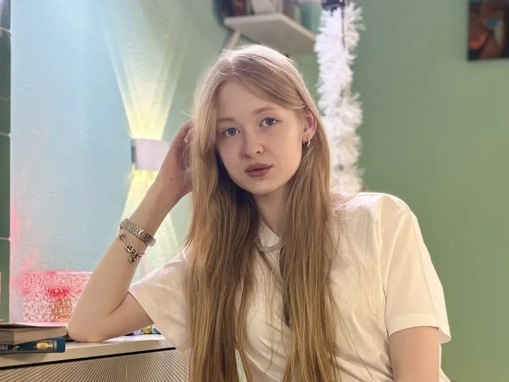 Blonde woman in a white t-shirt relaxing in a bright, cozy room with soft lighting.