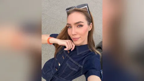 AmiliRay — AmiliRay wears a dark denim shirt and sunglasses on her head while posing outdoors.