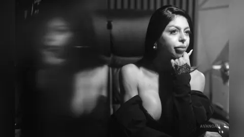 AvaNoah — AvaNoah poses in a black off-the-shoulder top with her hand resting on her chin in this black and white photo.
