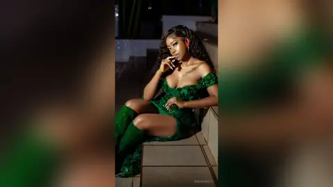 Elegant woman in a sparkling green cocktail dress sitting outdoors at night with a glamorous mood.