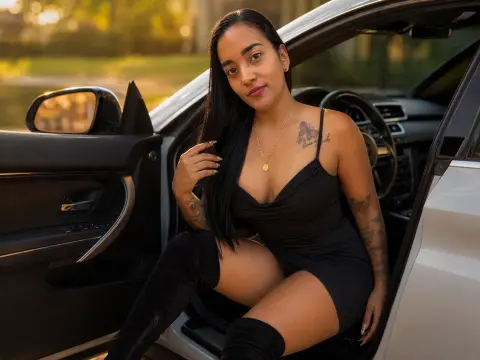 Elegant woman in a black mini dress and over-the-knee boots sitting in a luxury car during golden hour.