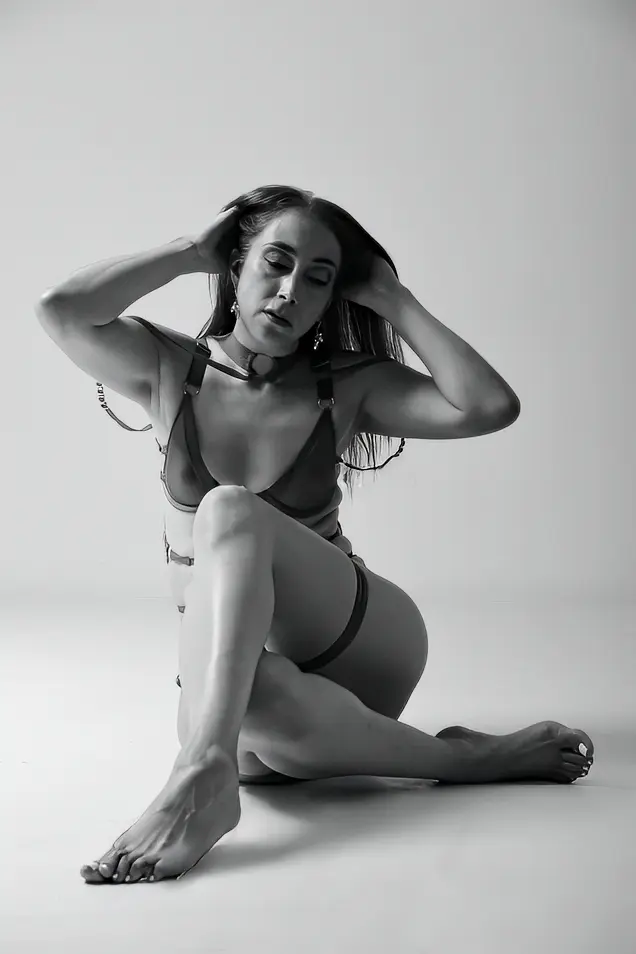 PrettyLady74 — Elegant woman in minimalist black lingerie posing gracefully in a studio setting, black and white portrait.