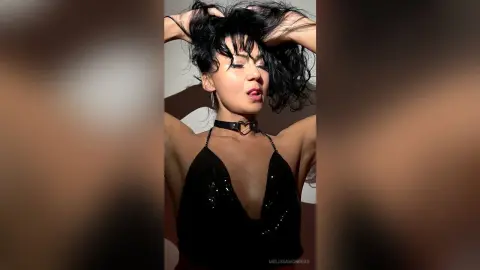 Glamorous woman in a black sequin halter dress and heart choker posing against a neutral studio background.