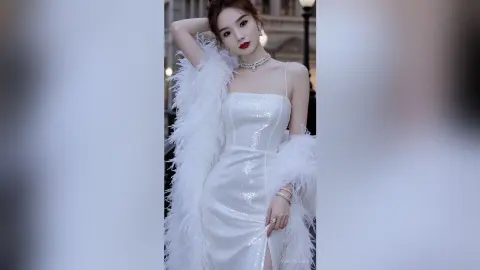 Elegant woman in a white sequin evening gown and feather boa posing glamorously in a city setting.