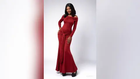 Smiling woman in a long-sleeved red maxi dress posing against a white studio background.