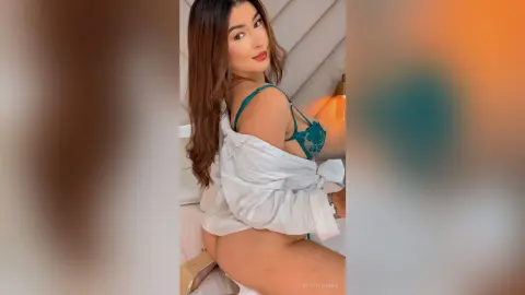 BeckyLeinner poses in a white button-down shirt and green lace bra, showing her bare buttocks and back while looking over her shoulder.