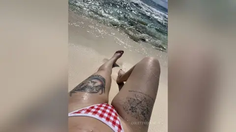 Tanned woman in red and white gingham bikini relaxing on a sunny tropical beach by the ocean waves.