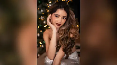 Glamorous woman in a silver sequin dress posing against a festive bokeh Christmas tree background.
