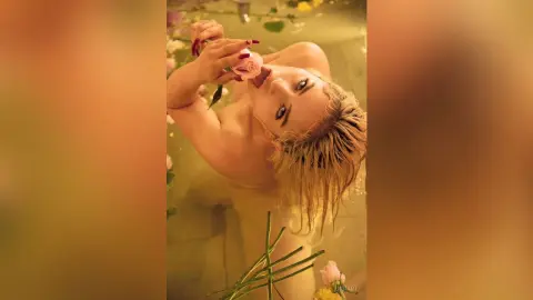 Blonde woman relaxing in a dreamy rose petal bath for a romantic and serene spa mood.