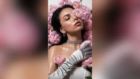 Glamorous woman in silver gloves and choker posing amidst soft pink peonies for a dreamy, romantic portrait.